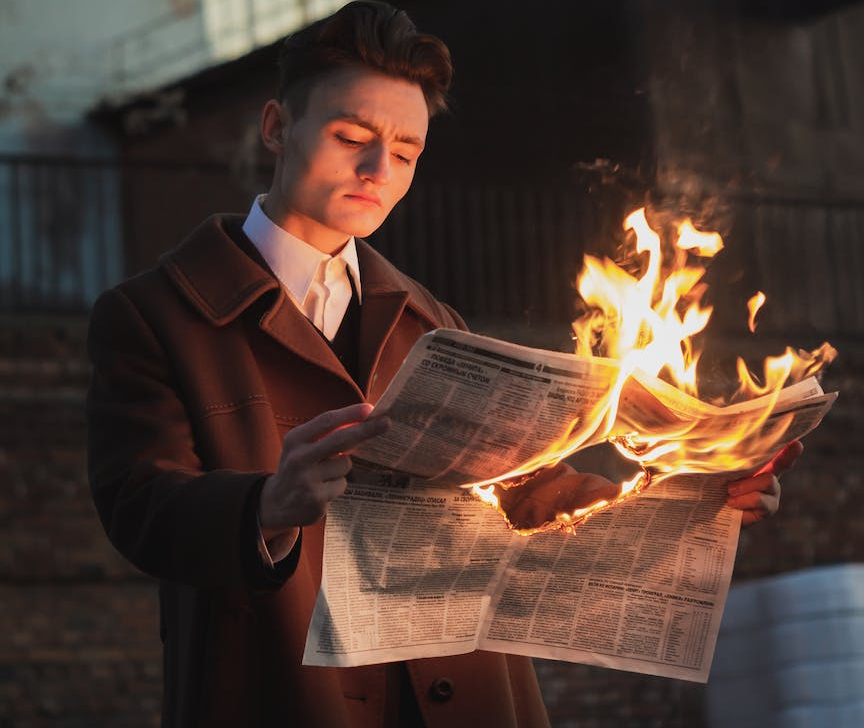 man reading burning newspaper